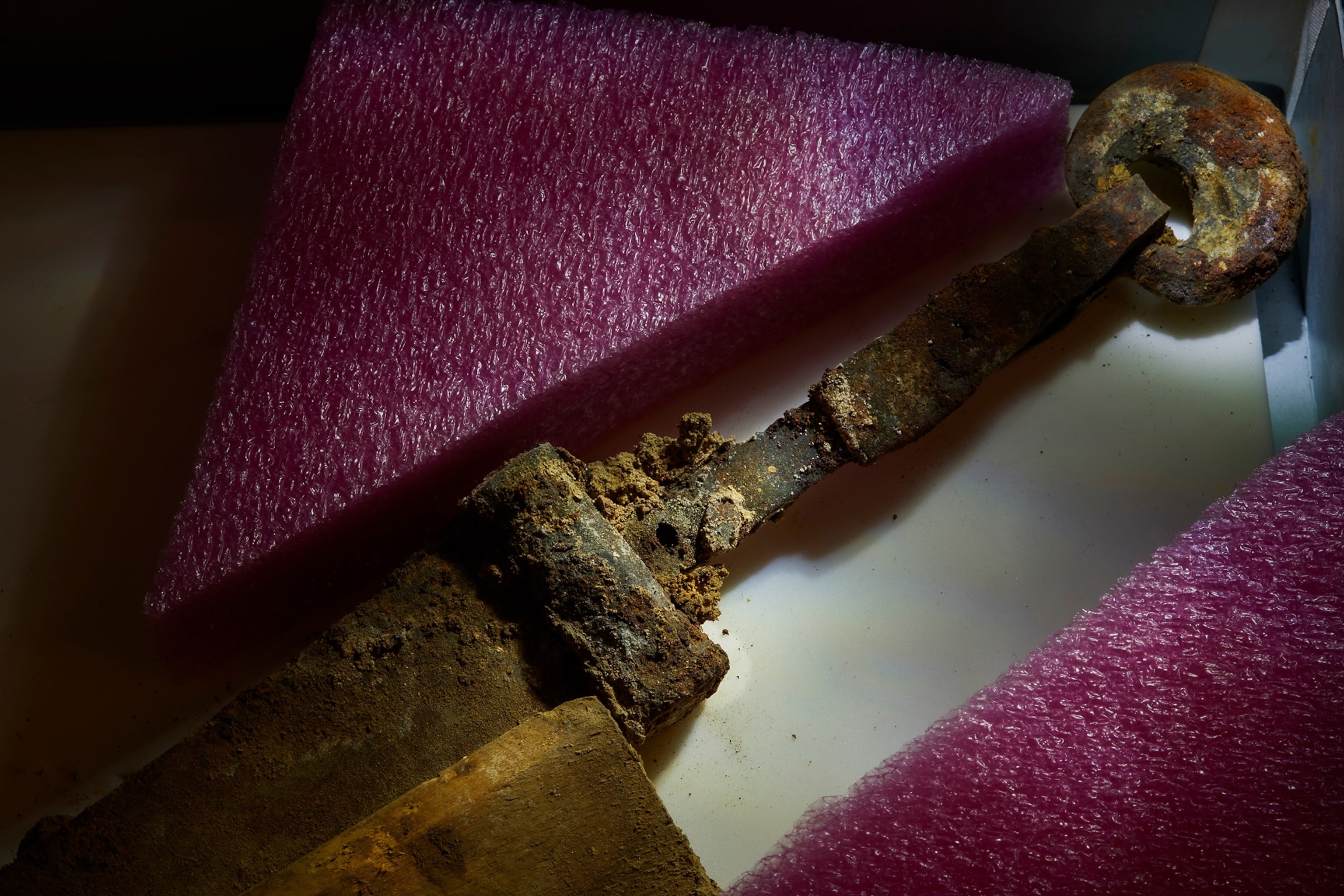 The ring-pommel sword lays on a table with purple form protection around it.